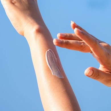 Mulher aplica o protetor solar corporal para garantir a proteção contra os raios solares