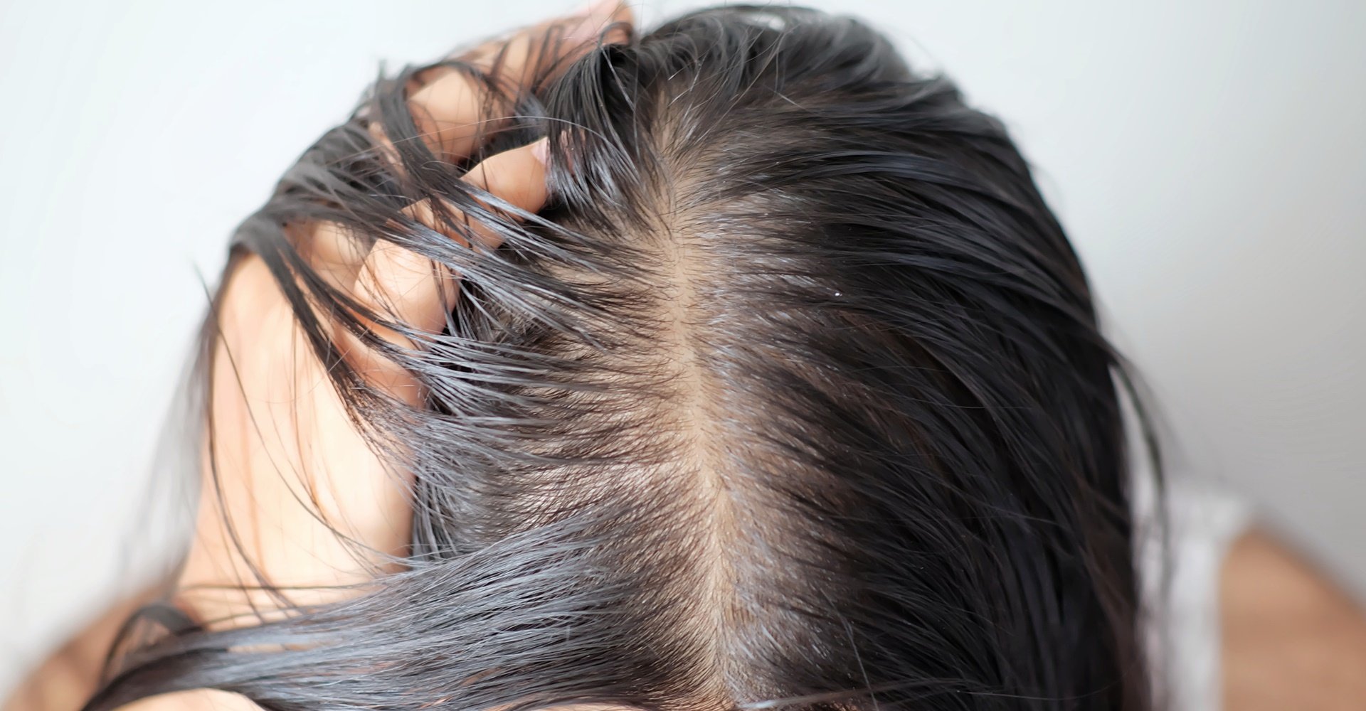 Modelo branca com expressão de espanto observando as pontas do seu cabelo