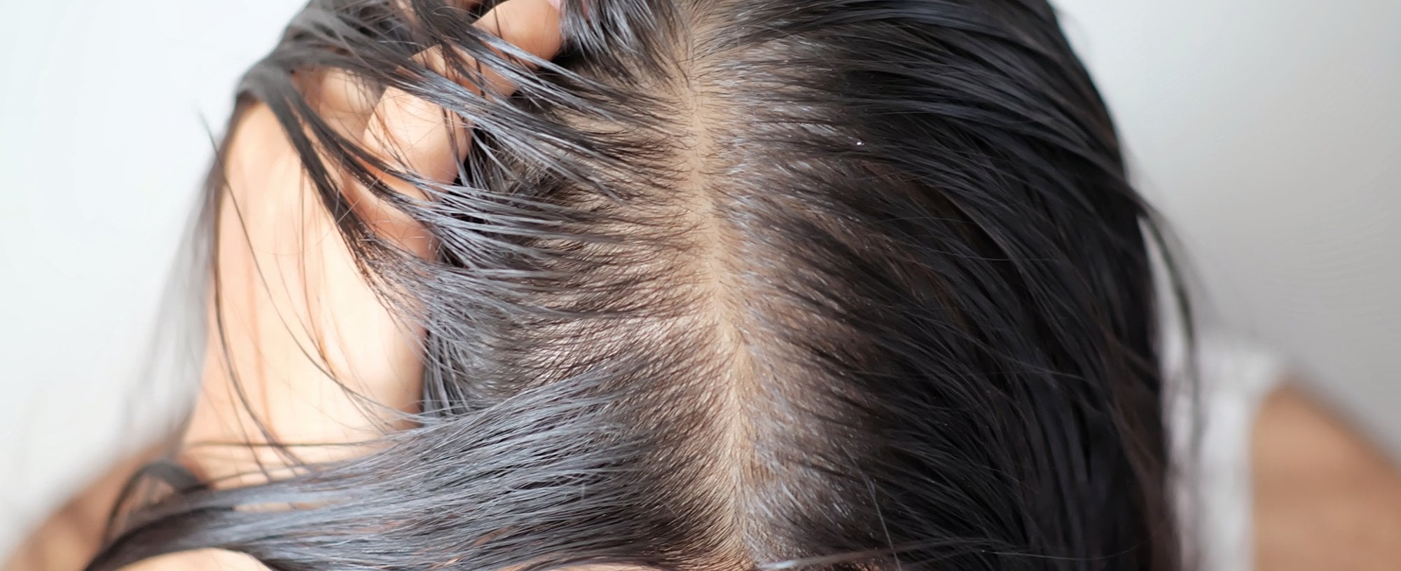 Modelo branca com expressão de espanto observando as pontas do seu cabelo