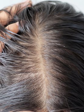 Modelo branca com expressão de espanto observando as pontas do seu cabelo