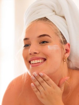 Mulher aplicando protetor solar facial para evitar o envelhecimento precoce