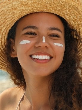 Modelo branca passando protetor solar no braço