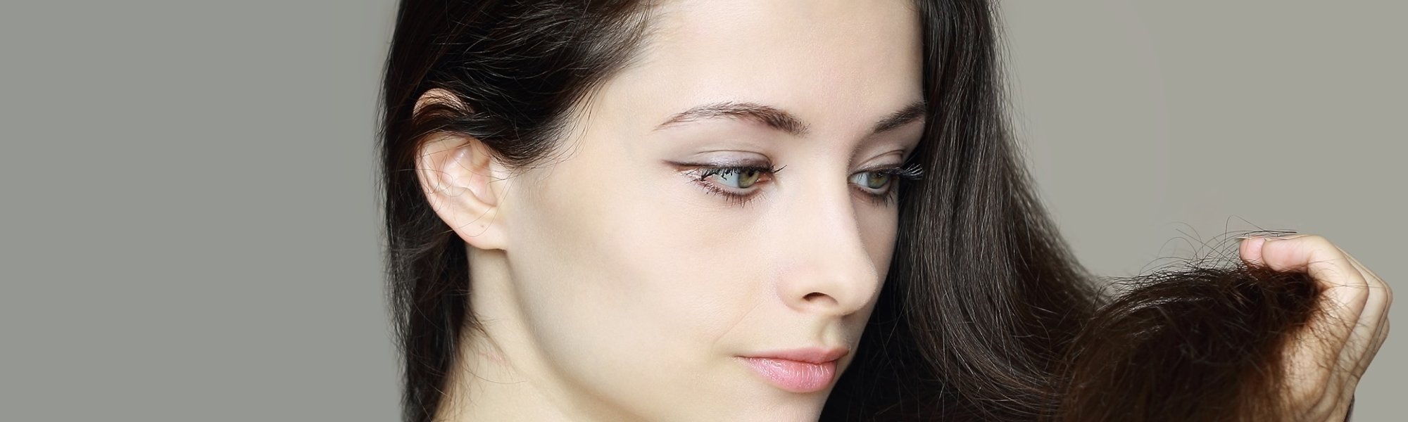 mulher de cabelos lisos segurando os fios com as pontas danificadas