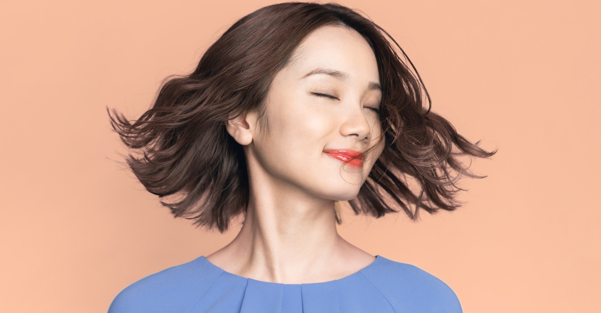 mulher asiática de cabelo curto virando o rosto e posando para a fotos