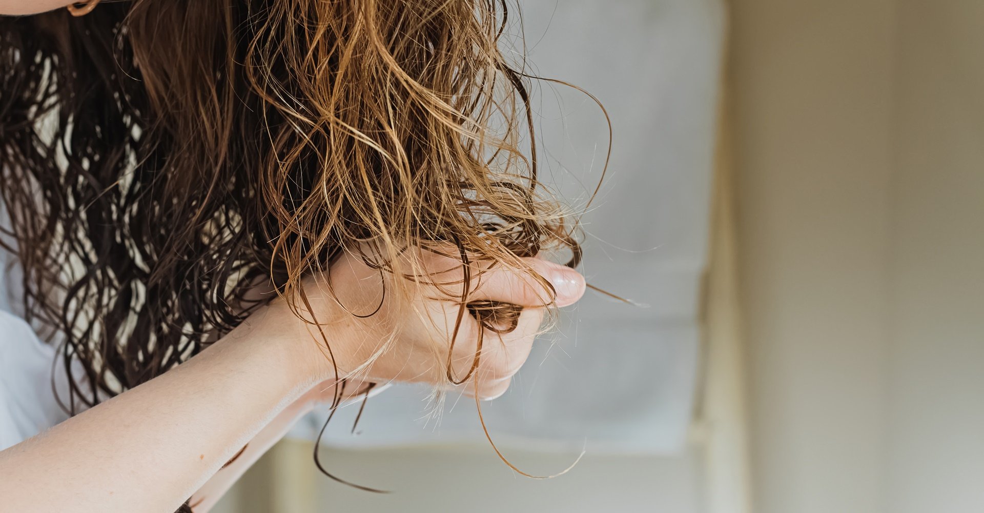 mulher de cabelo ondulado amassando os cabelos 