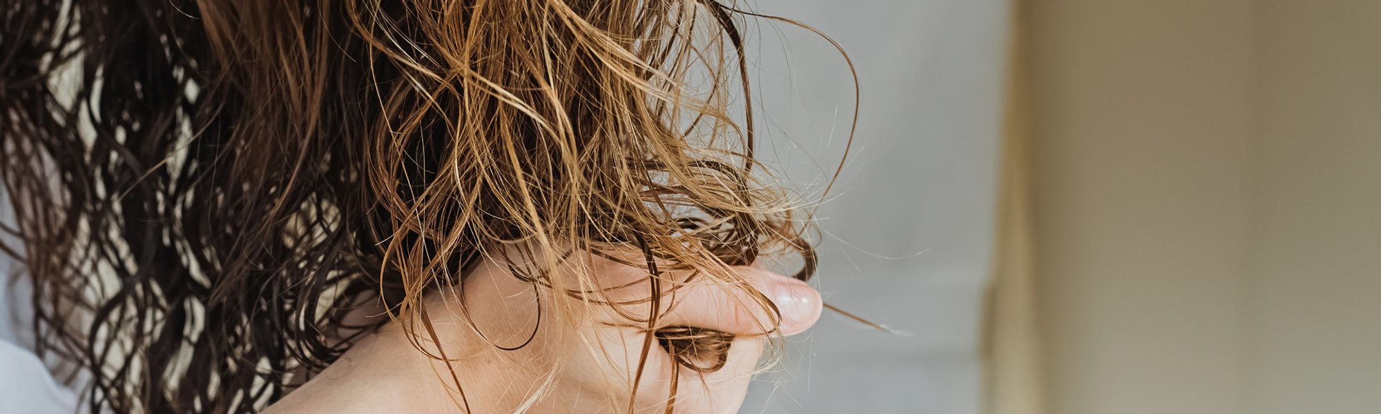 mulher de cabelo ondulado amassando os cabelos