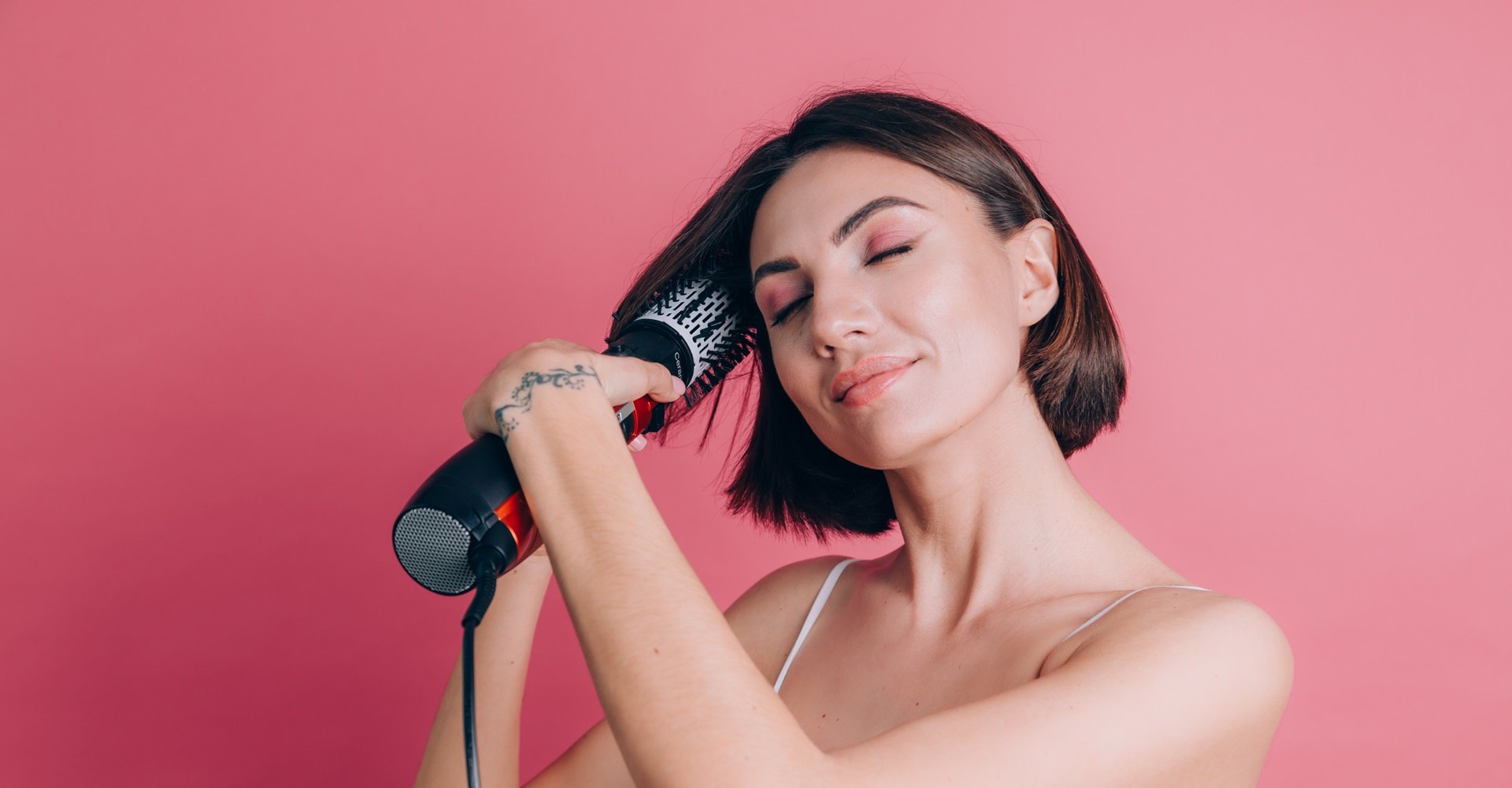 mulher de cabelo curto alisando o seu cabelo com uma escova alisadora