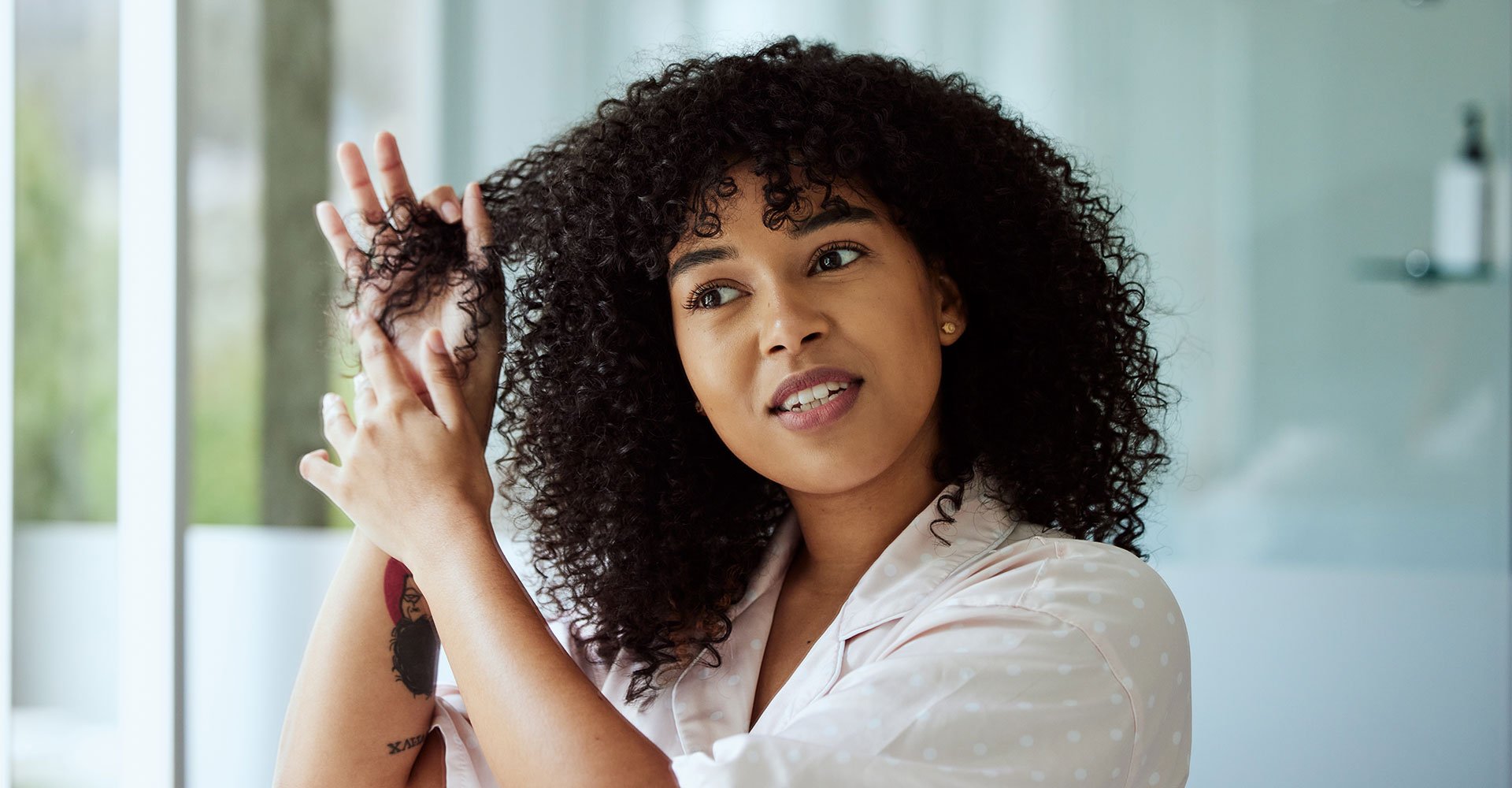 Mulher com o cabelo cacheado usa gelatina de cabelo para definir seus cachos