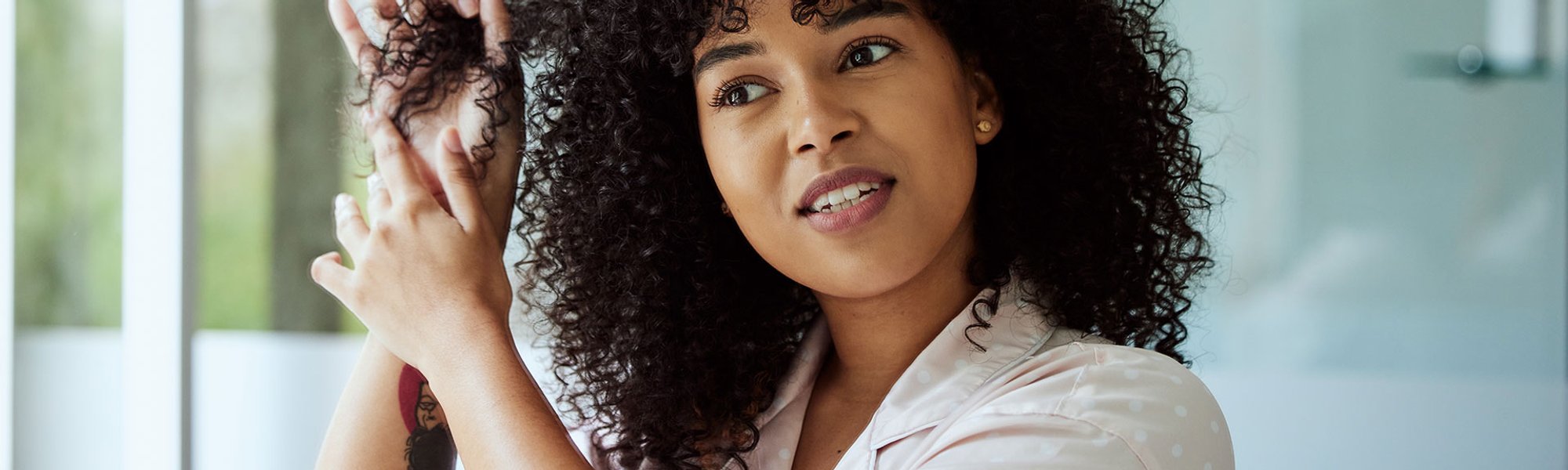 Mulher com o cabelo cacheado usa gelatina de cabelo para definir seus cachos