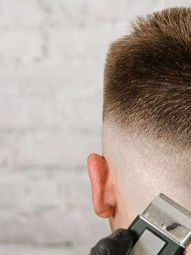 Jovem recebe um corte high fade estiloso em barbearia moderna