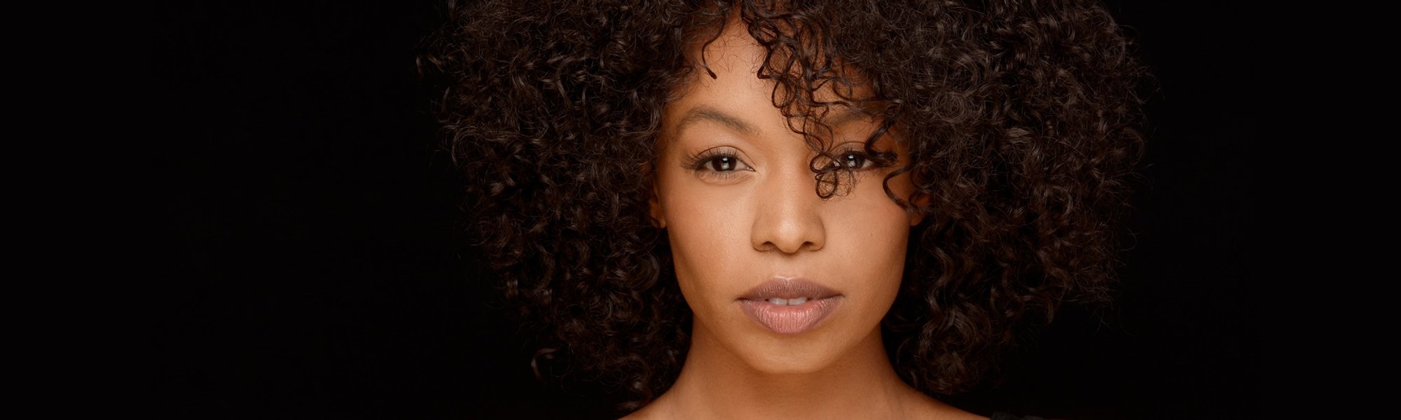 mulher de cabelo cacheado visivelmente hidratado posando para a foto