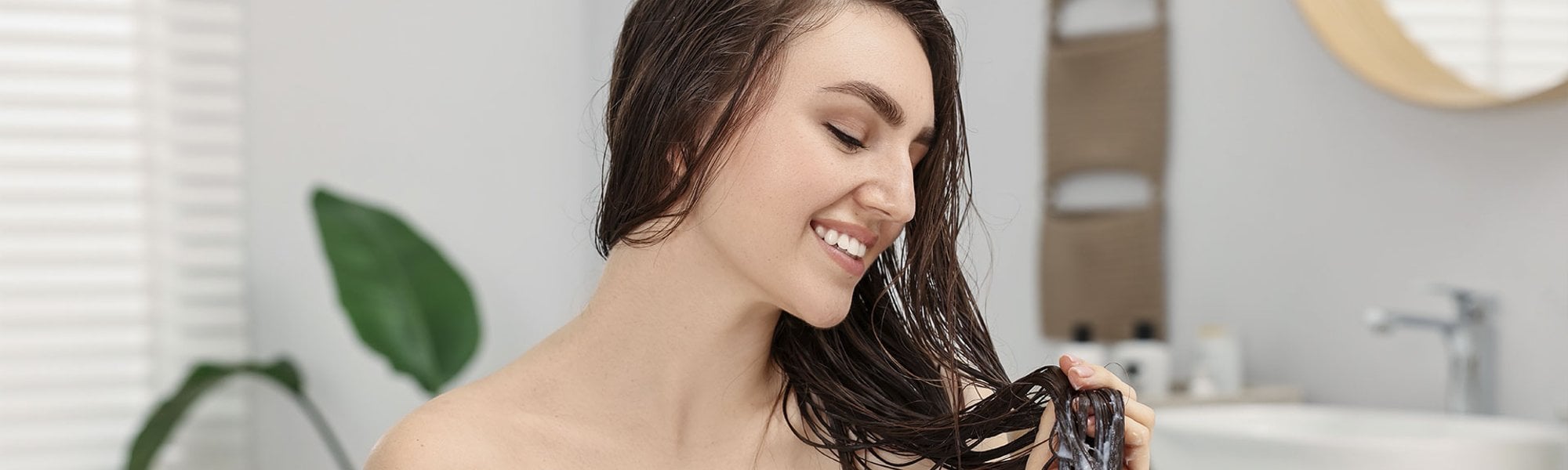 Mulher caucasiana aplica máscara capilar no comprimento de seu cabelo liso e longo