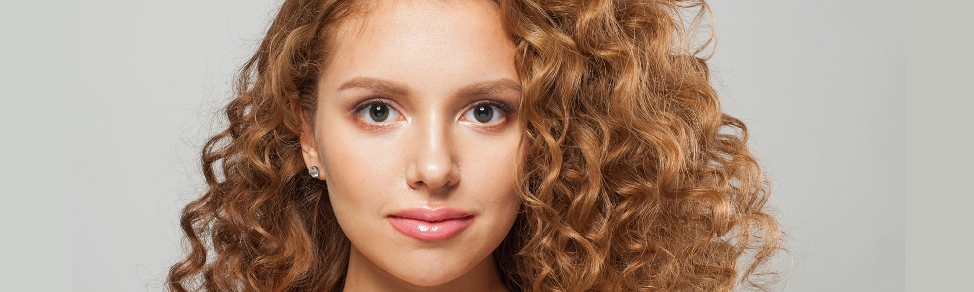 Ruiva com cabelo cacheado faz uso de mascara de nutrição capilar