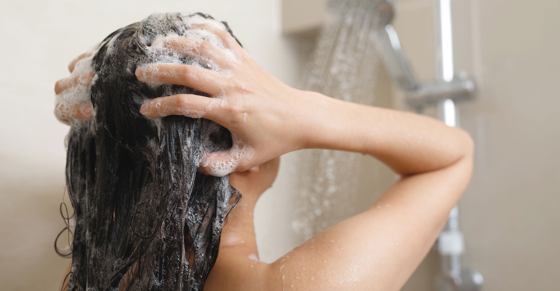 Mulher lava o cabelo para tirar sujeira e oleosidade que o pré-poo impede de ser removida em excesso para não ressecar