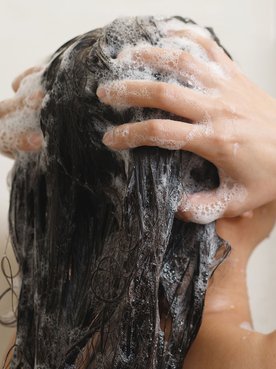 Mulher lava o cabelo para tirar sujeira e oleosidade que o pré-poo impede de ser removida em excesso para não ressecar