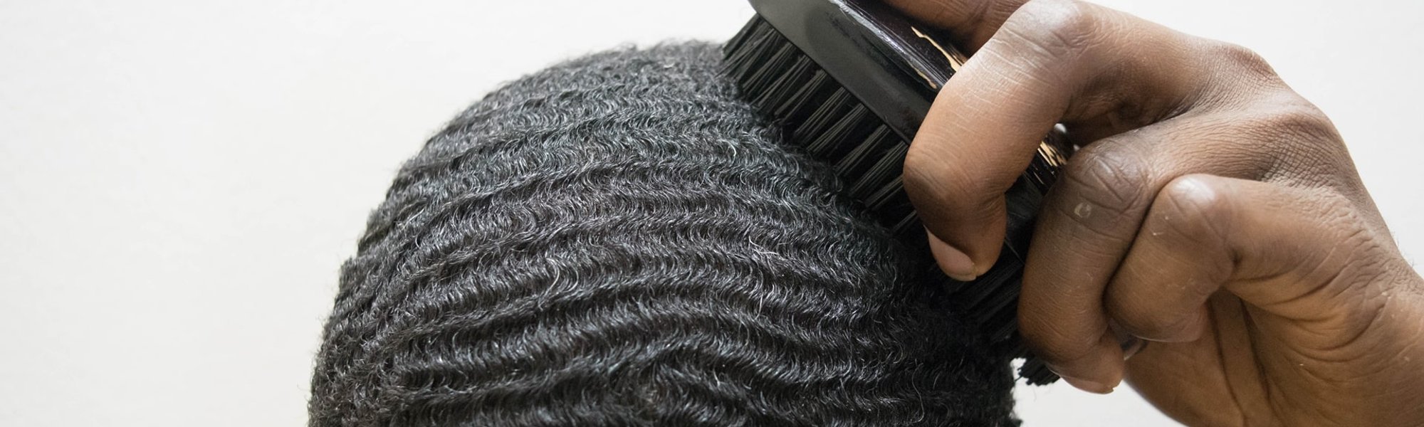 Homem penteia o cabelo crespo formando ondas conhecidas como waves no cabelo