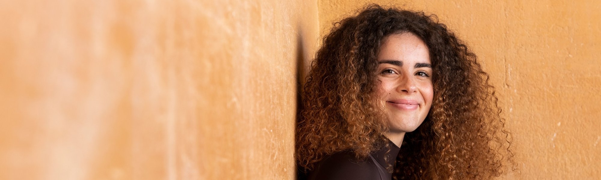 mulher com cabelo cacheado com pontas morena iluminada