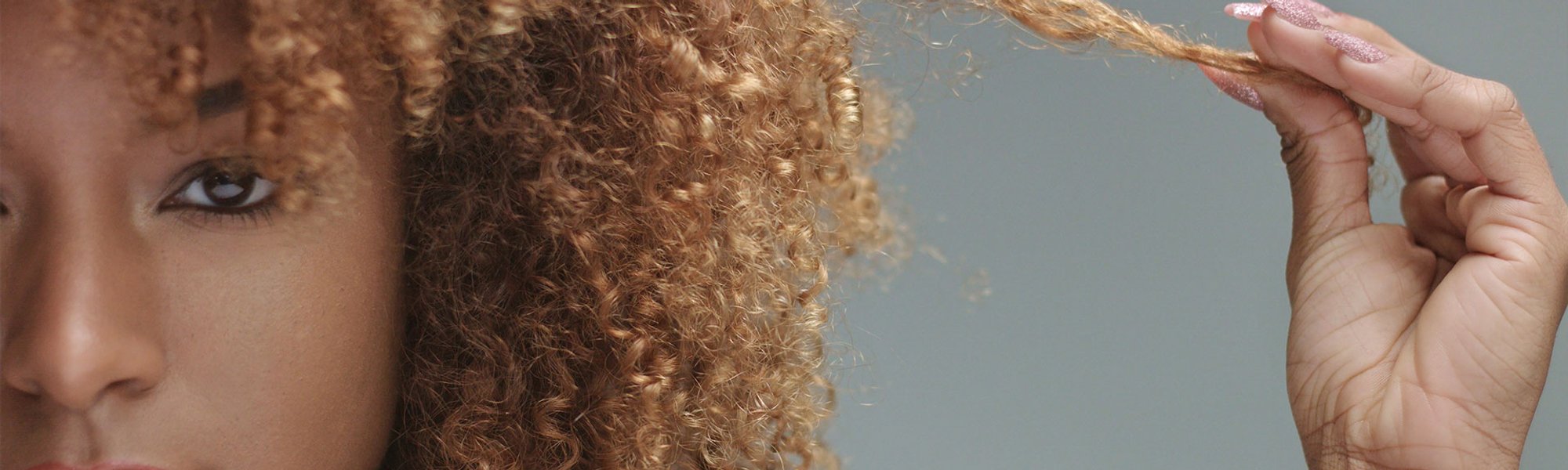 mulher negra com cabelo cacheado com tom loiro quente