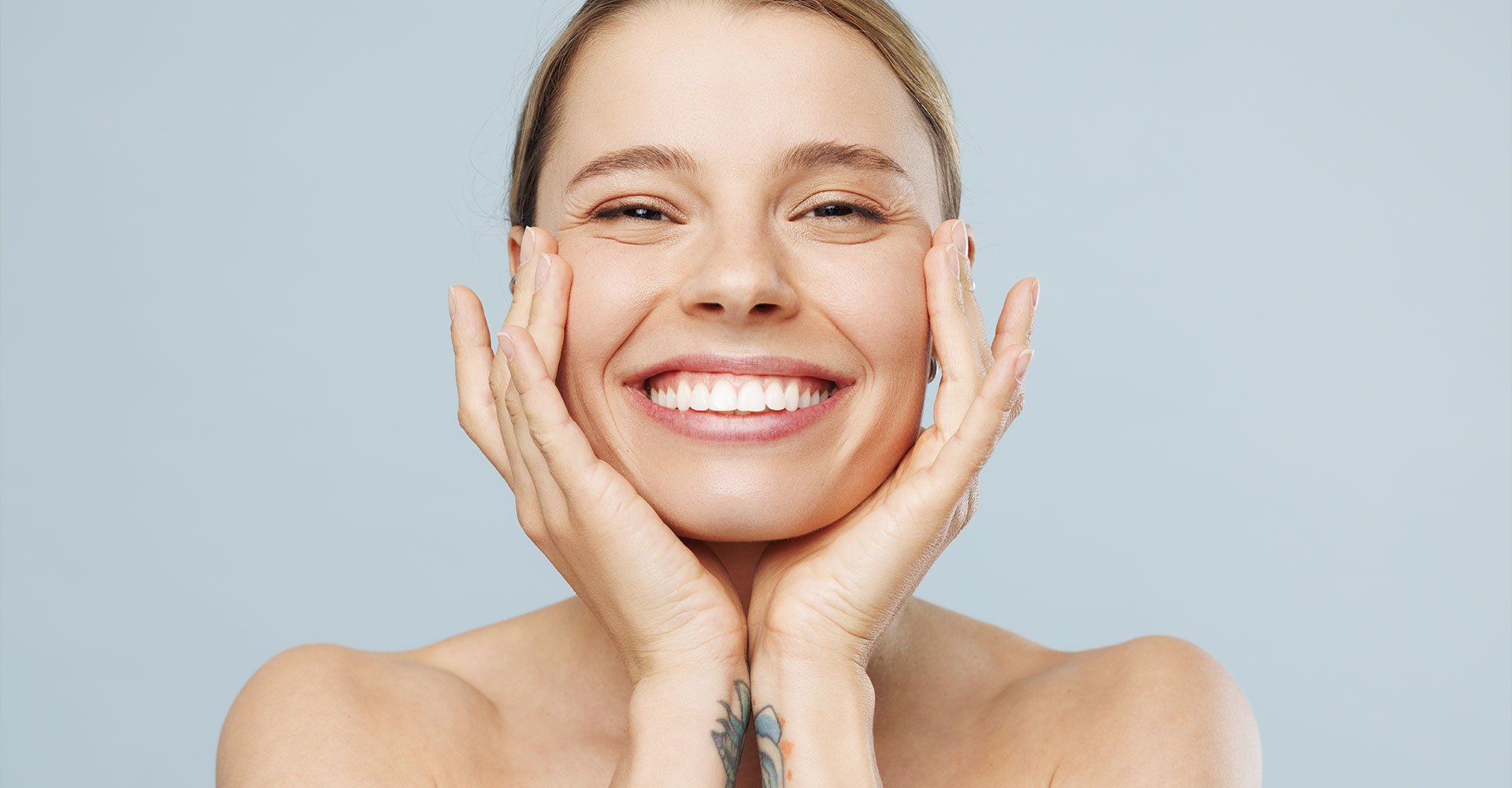 mulher branca esticando parte do seu rosto para demonstrar a elasticidade da pele