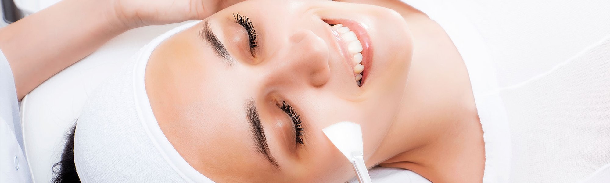 Mulher sorrindo ao fazer o tratamento de peeling facial que pode ser químico ou físico