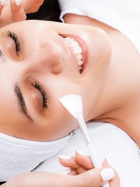 Mulher sorrindo ao fazer o tratamento de peeling facial que pode ser químico ou físico