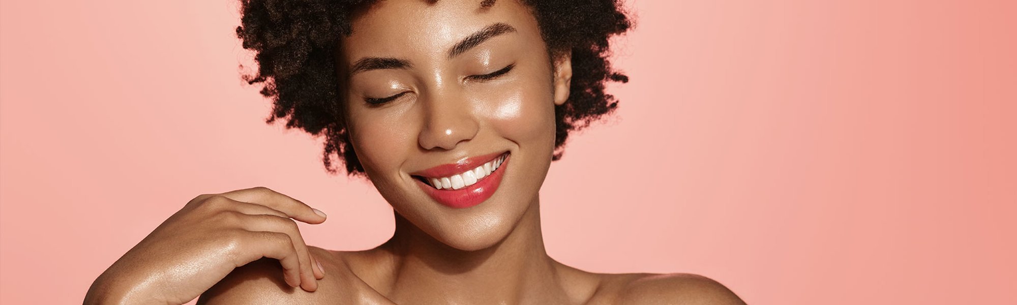 Mulher negra com glass skin sorri com efeito glow na pele