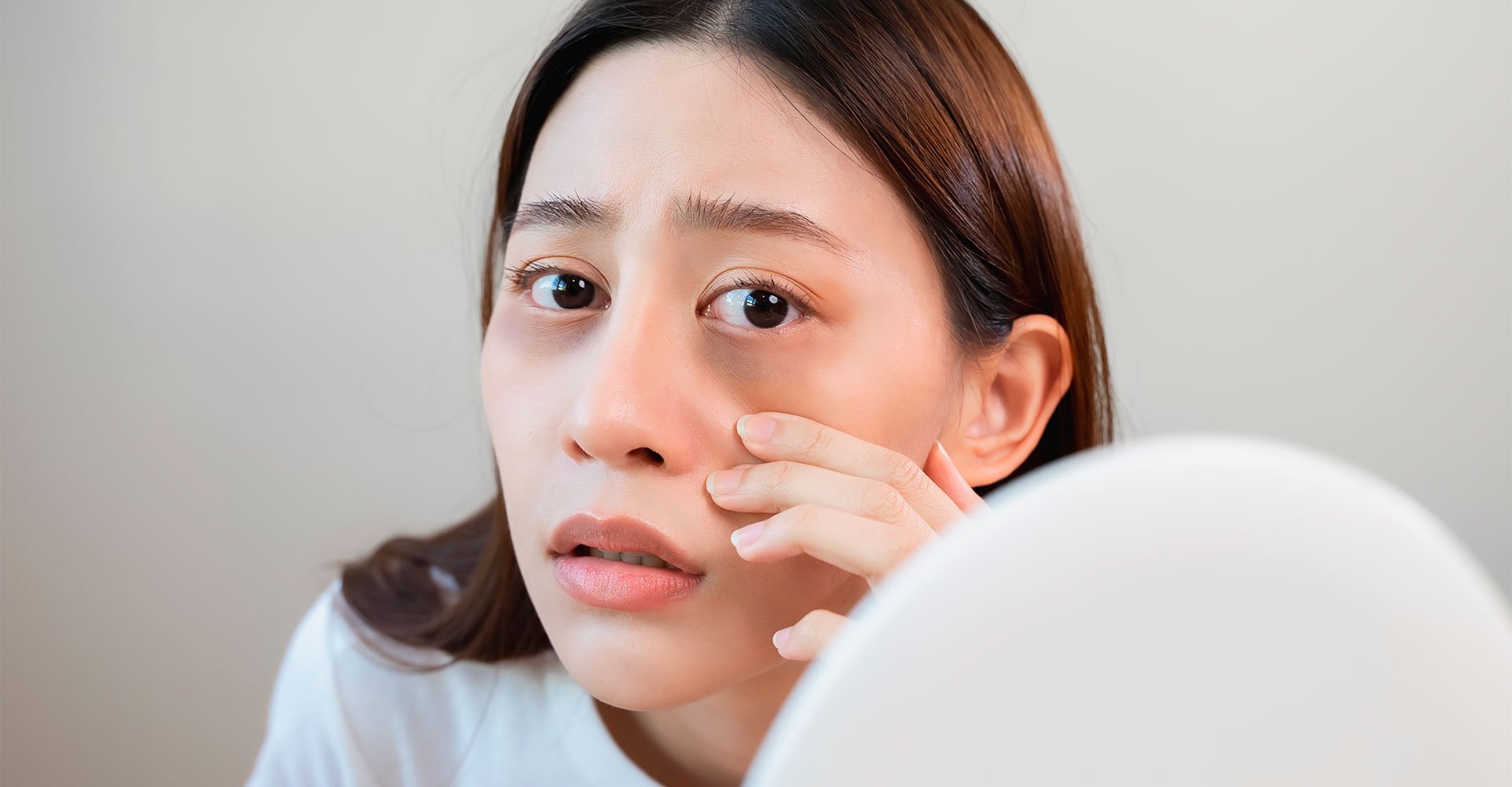 Mulher jovem asiática analisa as olheiras em seu rosto