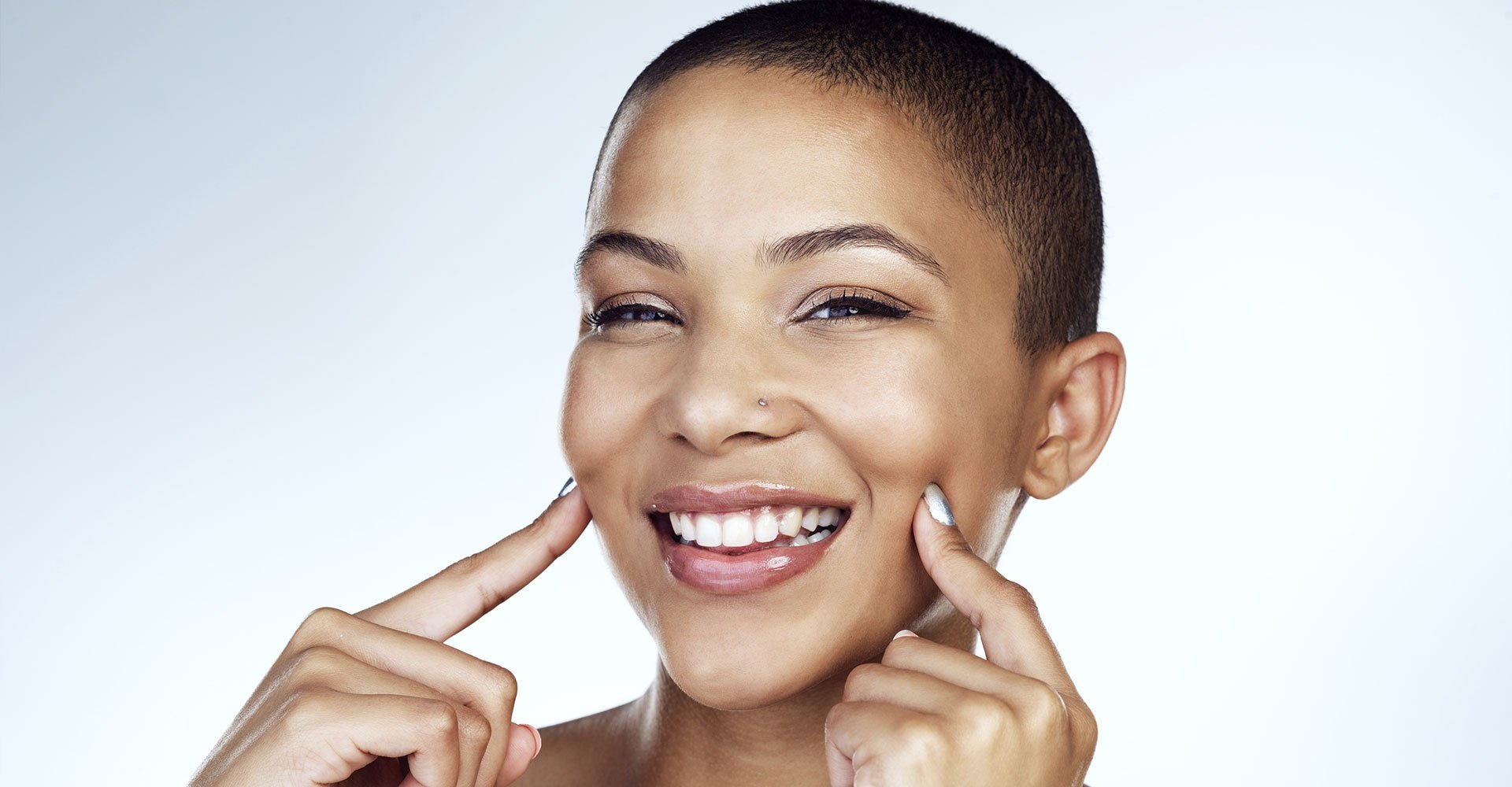 mulher negra sorrindo para a foto com os dedos levemente apoiados no rosto