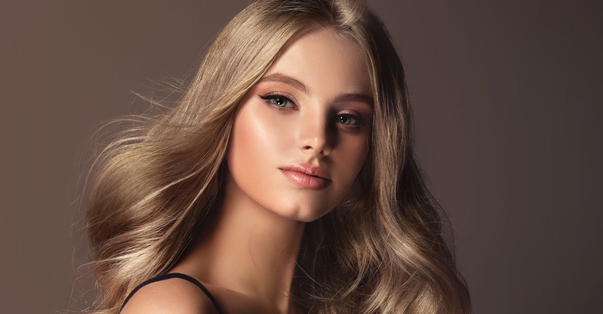 Mulher com cabelo loiro aos ventos após fazer técnica de escovação blow out em seus fios.