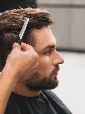 Homem cortando seu cabelo com barbeiro no corte social masculino.