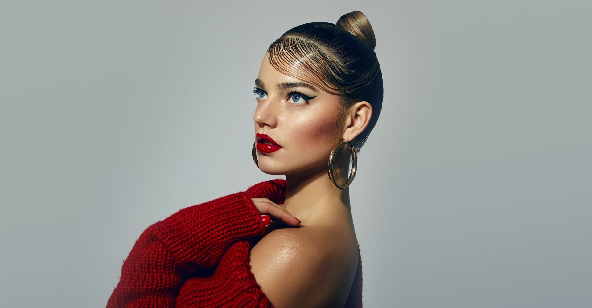 Menina olhando para cima com blusa vermelha e gel no coque alto.