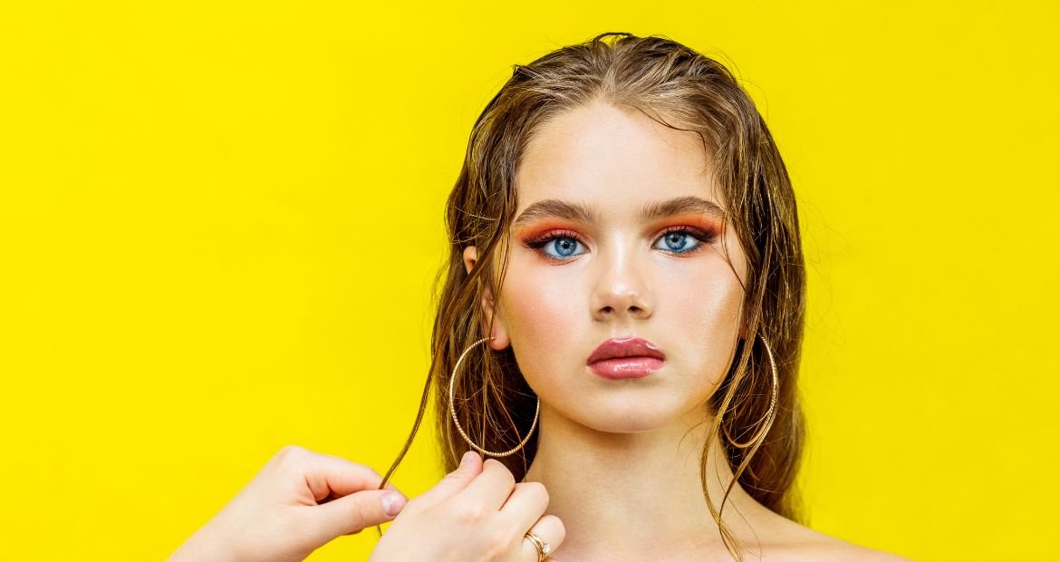 Menina com gel no cabelo loiro em fundo amarelo.
