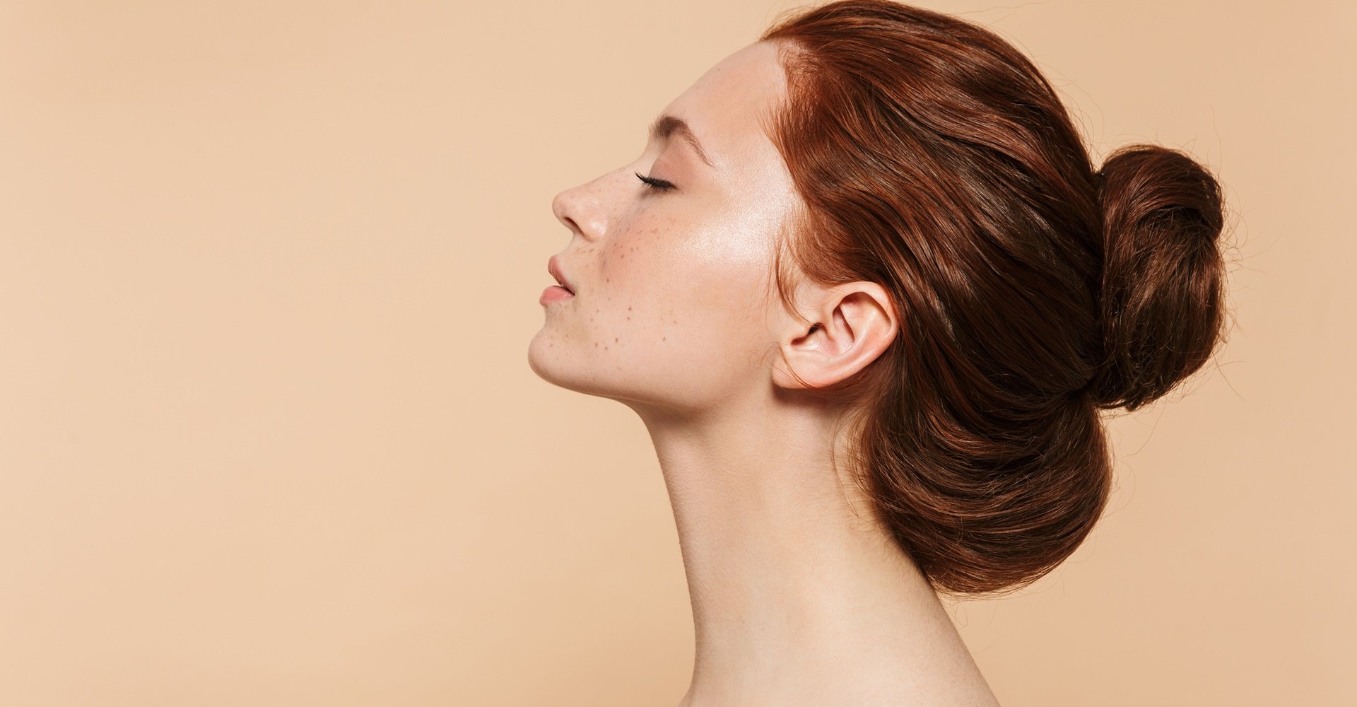 Mulher com os olhos fechados com coque no cabelo ruivo