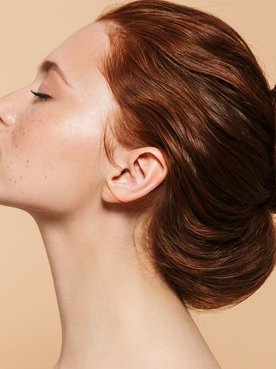 Mulher com os olhos fechados com coque no cabelo ruivo