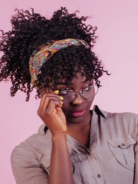 Mulher com bandana no seu cabelo cacheado curto.