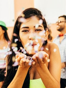 Menina soprando glitter no carnaval.