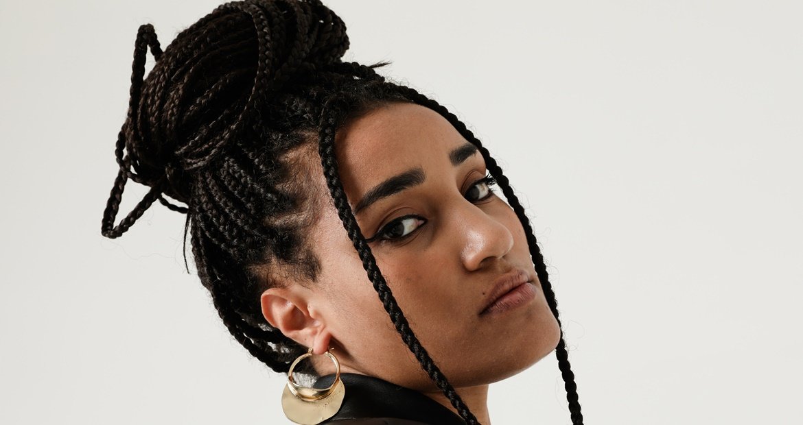 Mulher morena com trança e coque no cabelo longo.