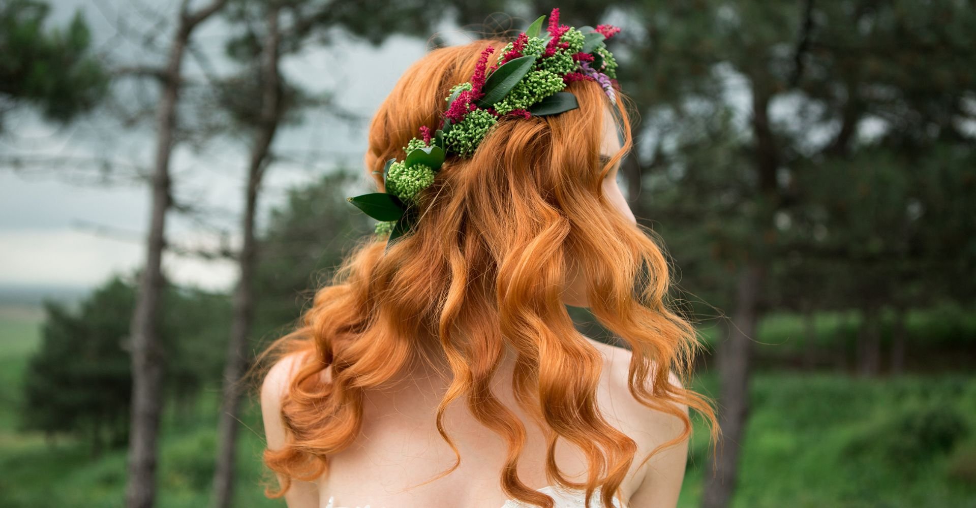 Mulher em uma floresta com penteado simples em seu cabelo ruivo.