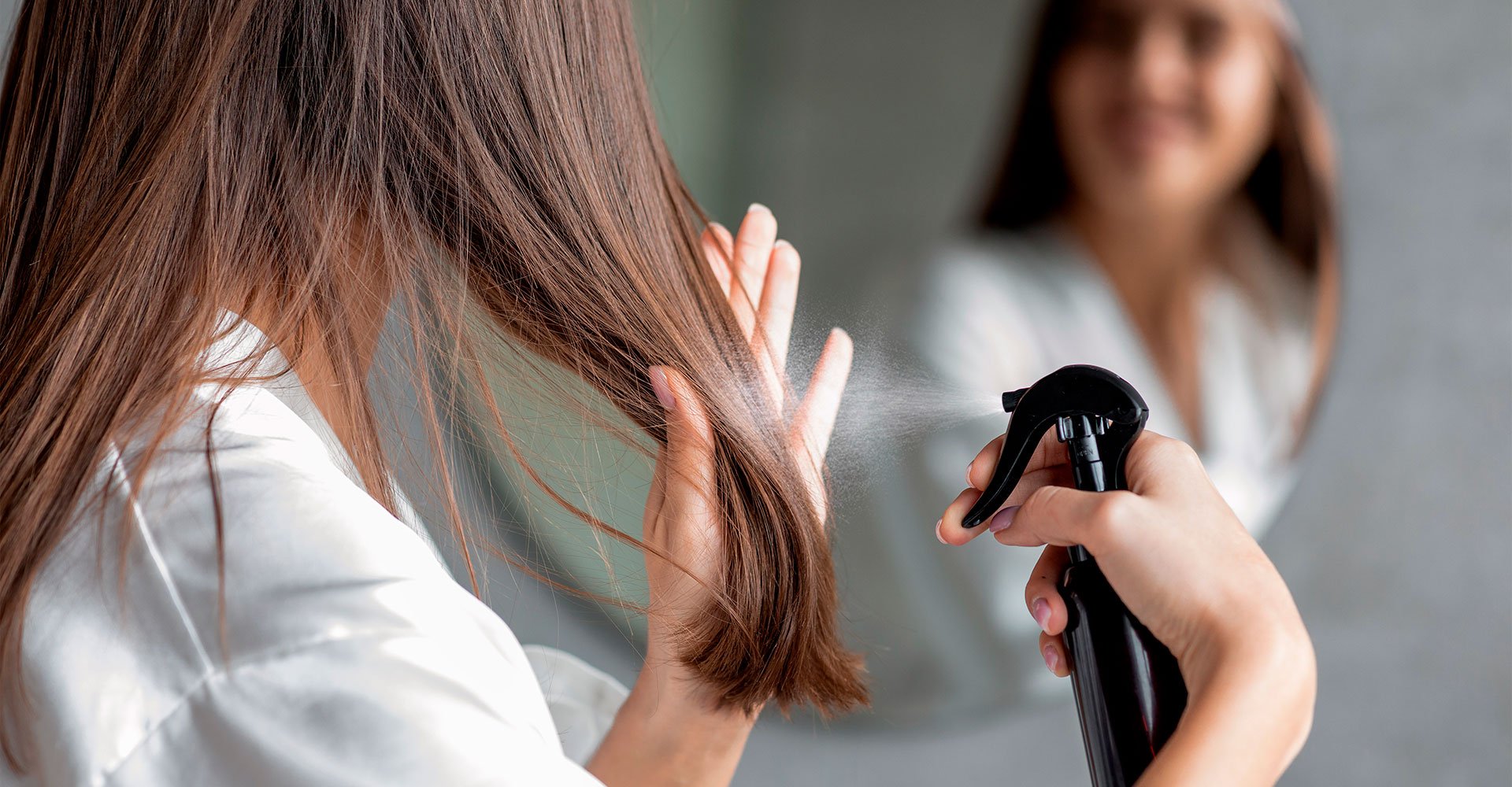 Mulher branca passando protetor térmico no cabelo para proteger os fios no verão.