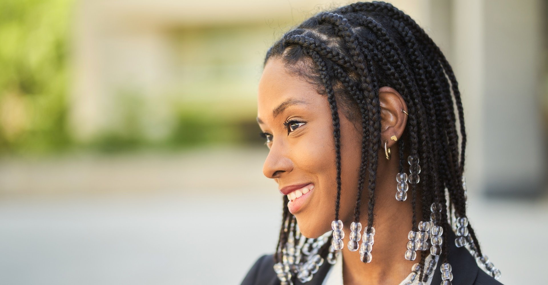 Mulher negra com trança em cabelo curto e acessórios na ponta.