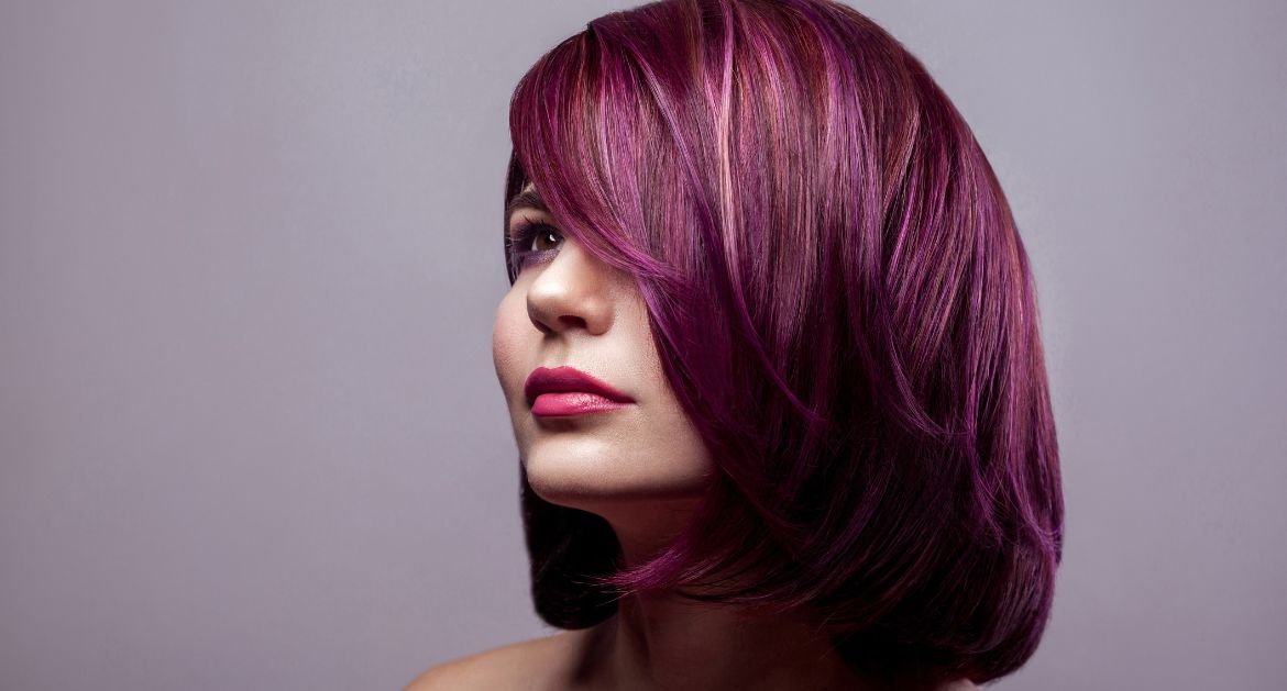 Mulher olhando para o horizonte com tom de cabelo acaju púrpura no cabelo curto.