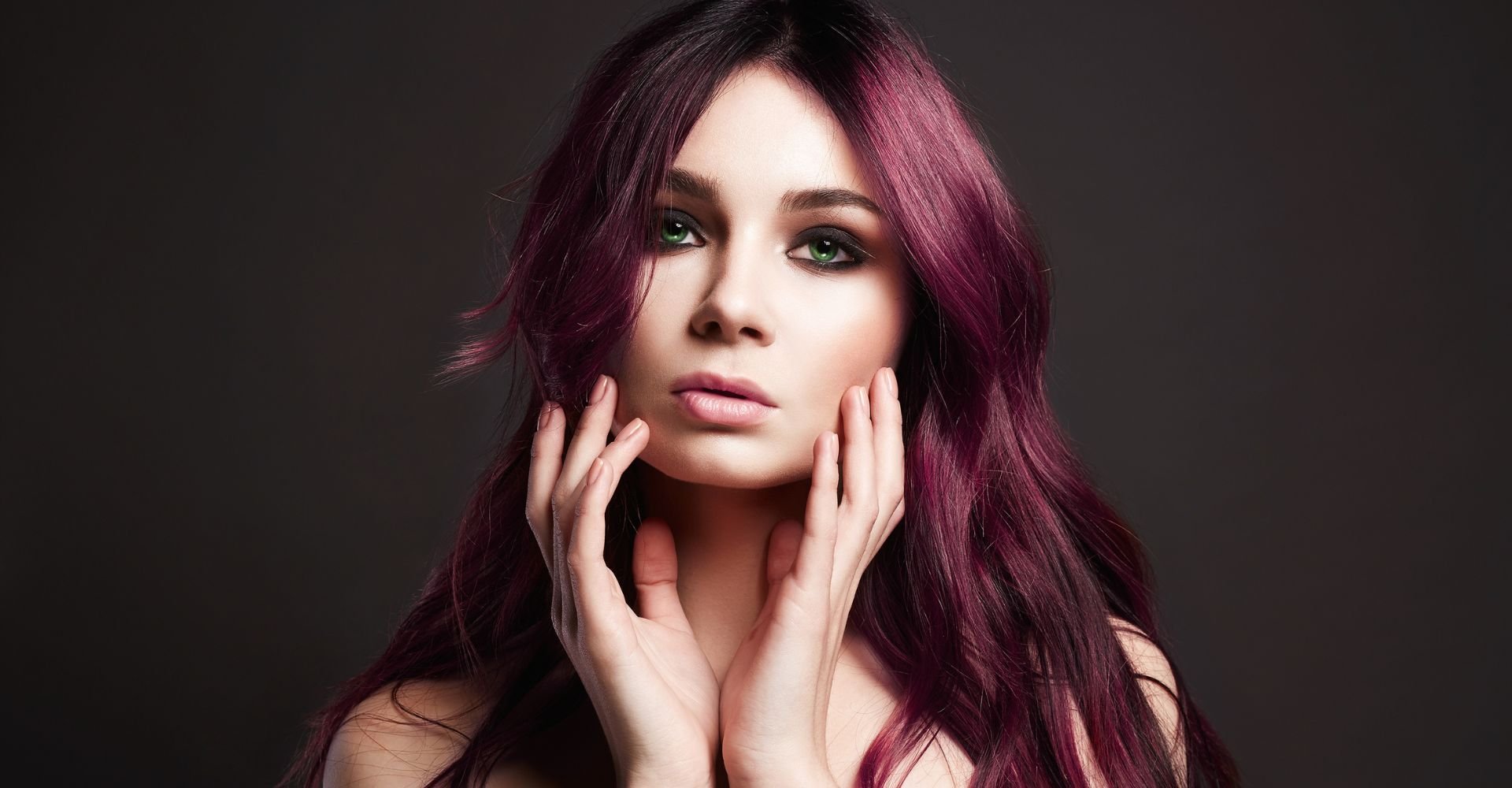 Mulher com as duas mãos tocando o rosto com cor de cabelo acaju púrpura