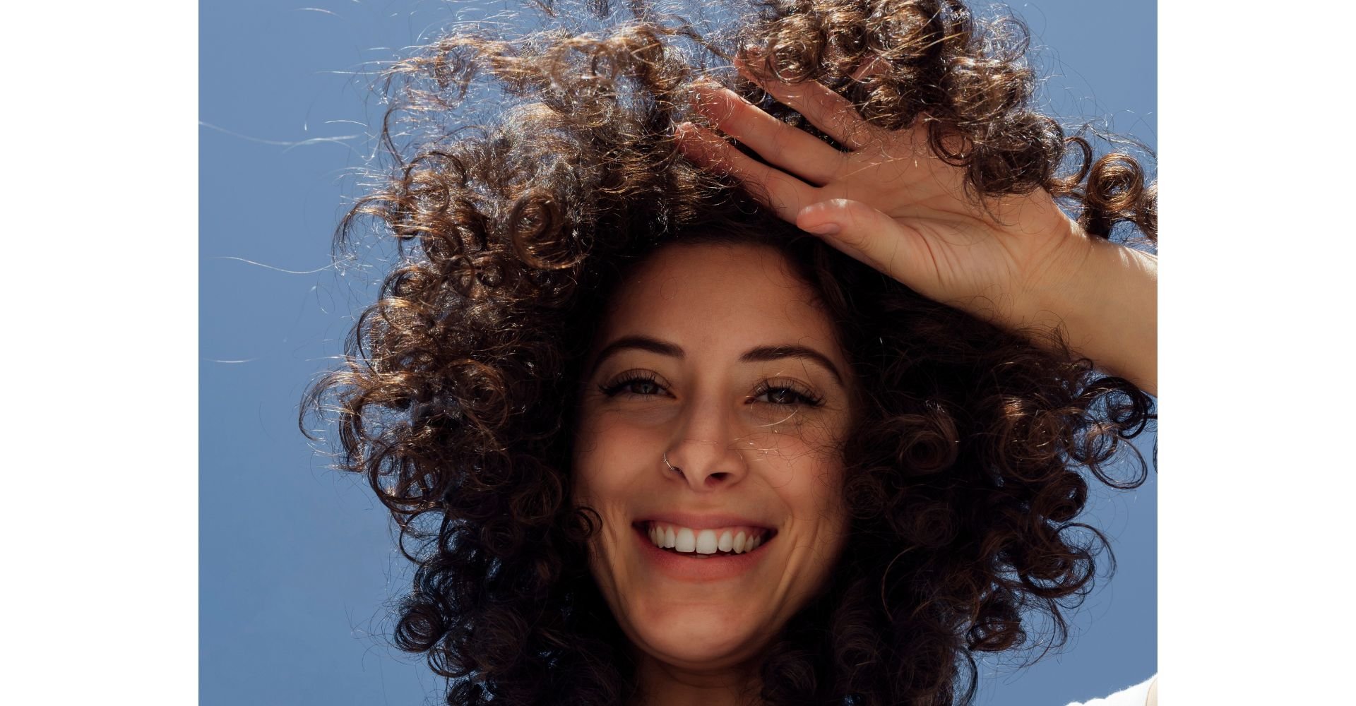 Mulher sorrindo com cabelo cacheado castanho claro natural