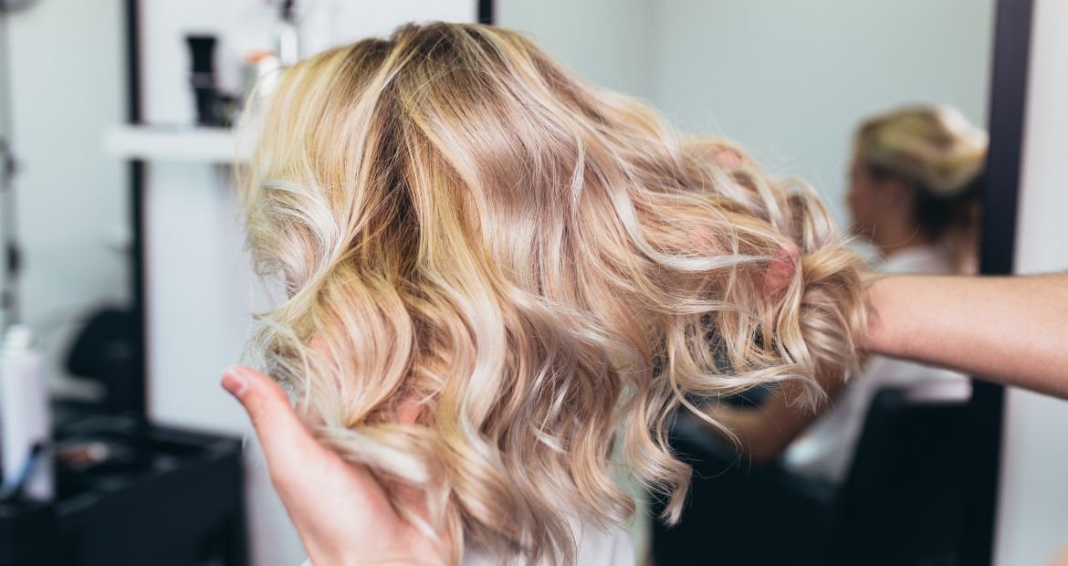 Profissional mostra cabelo iluminado curto e loiro com as pontas mais claras do que as raízes