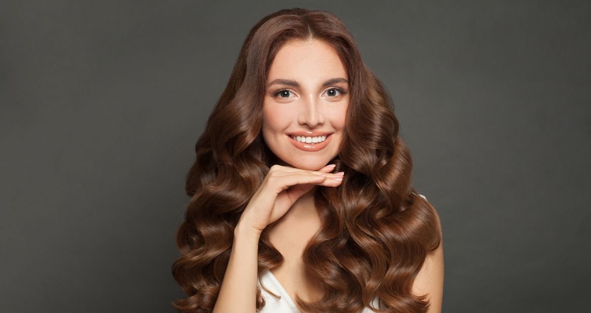 Mulher sorridente com cabelo em tom marrom chocolate.