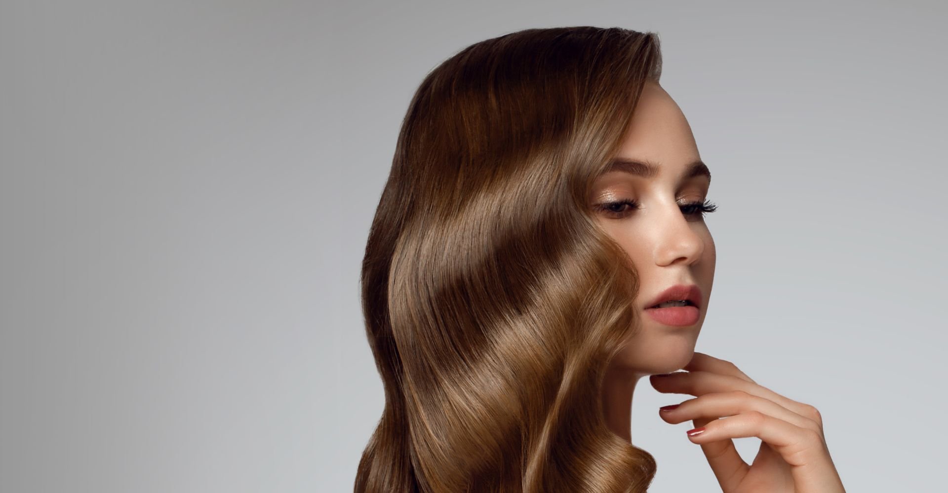 Mulher com cabelo loiro escuro com a mão no queixo.