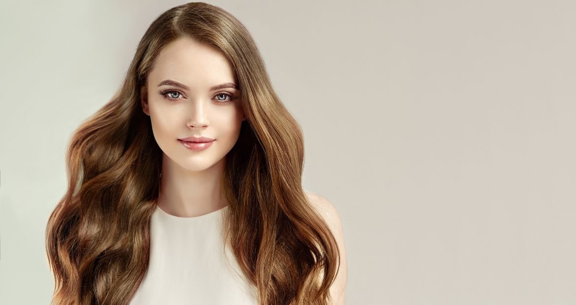 Mulher com cabelo loiro escuro e olhos verdes.