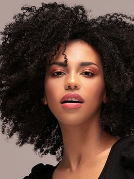 Mulher negra com o cabelo crespo e preto ao usar tinta preta para cabelo