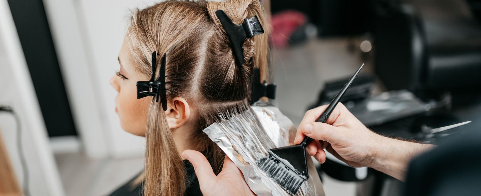 Profissional aplicando uma tinta de cabelo em sua cliente