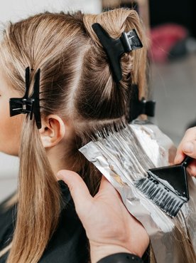 Profissional aplicando uma tinta de cabelo em sua cliente